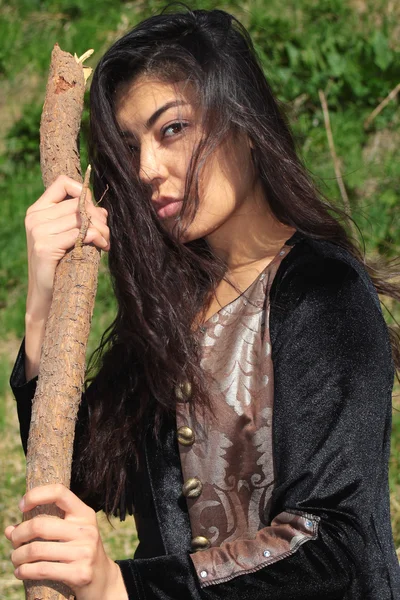 Frau im nationalen schwarzen Samtkleid mit einem Stock in der Hand und ausdrucksstarken Augen auf dem Hintergrund der Natur — Stockfoto