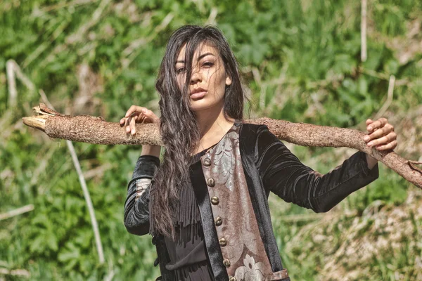 Mujer en vestido nacional de terciopelo negro con un palo en la mano y ojos expresivos en el fondo de la naturaleza — Foto de Stock