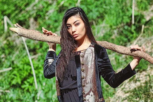 Frau im nationalen schwarzen Samtkleid mit einem Stock in der Hand und ausdrucksstarken Augen auf dem Hintergrund der Natur — Stockfoto