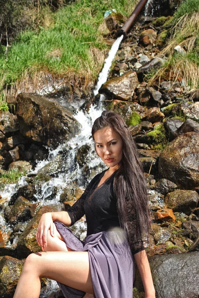 Woman posing on the rocks by the river — Stock Photo, Image