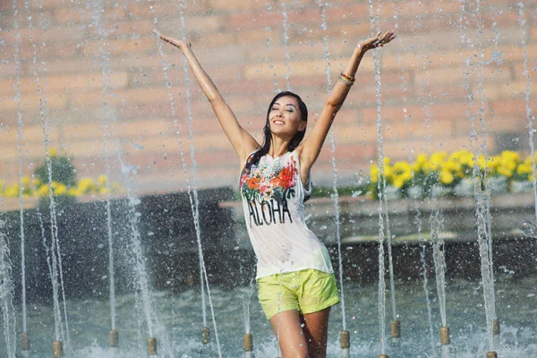 Fröhliches Mädchen tanzt unter Wasserstrahlen im Stadtbrunnen — Stockfoto
