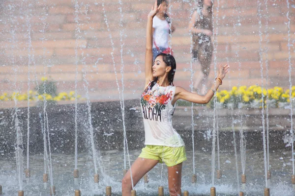 Cheerful girl dancing under jets of water in city fountain — Stock Photo, Image