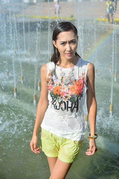 Cheerful girl dancing under jets of water in city fountain — Stock Photo, Image