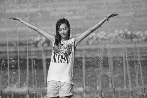 Chica alegre bailando bajo chorros de agua en la fuente de la ciudad —  Fotos de Stock