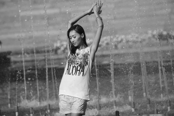 Весела дівчина танцює під струменями води в міському фонтані — стокове фото