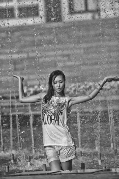 Menina alegre dançando sob jatos de água na fonte da cidade — Fotografia de Stock