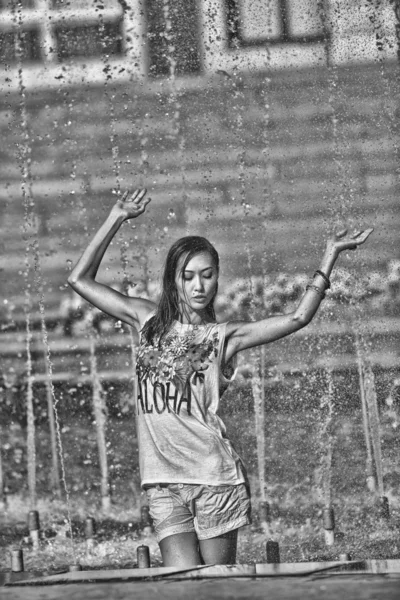 Chica alegre bailando bajo chorros de agua en la fuente de la ciudad —  Fotos de Stock