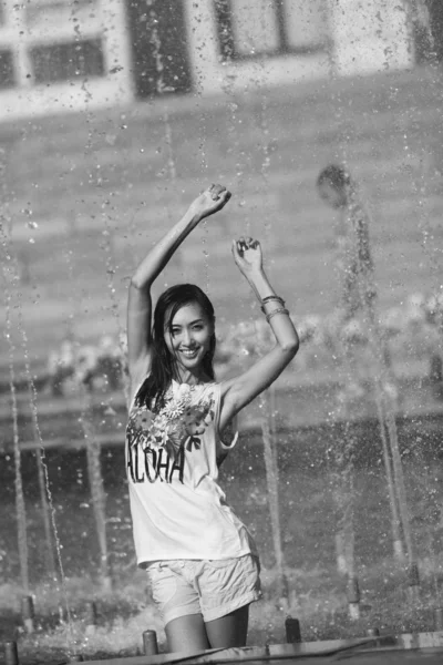 Chica alegre bailando bajo chorros de agua en la fuente de la ciudad —  Fotos de Stock