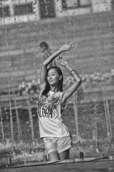 Chica alegre bailando bajo chorros de agua en la fuente de la ciudad —  Fotos de Stock