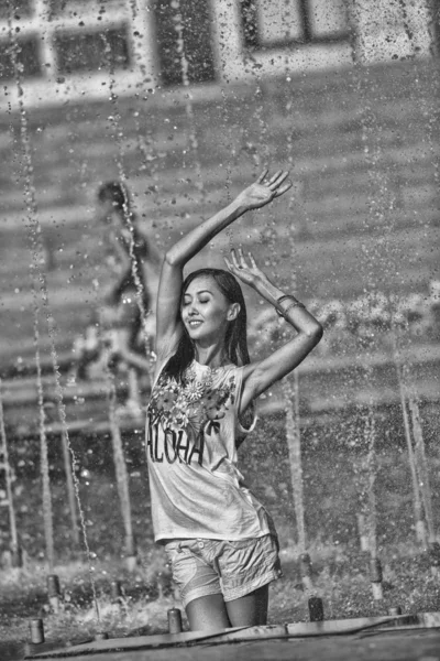 Chica alegre bailando bajo chorros de agua en la fuente de la ciudad —  Fotos de Stock