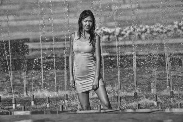 Девушка в облегающем платье с длинными волосами в капельках воды в городском фонтане — стоковое фото