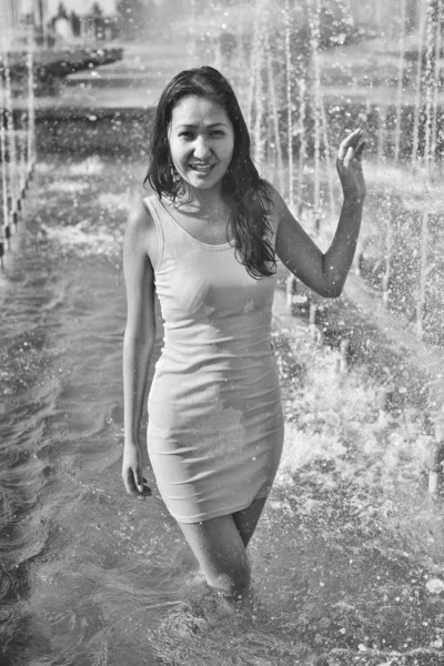 Girl in a slinky dress with long hair in water droplets in the city fountain — Stock Photo, Image