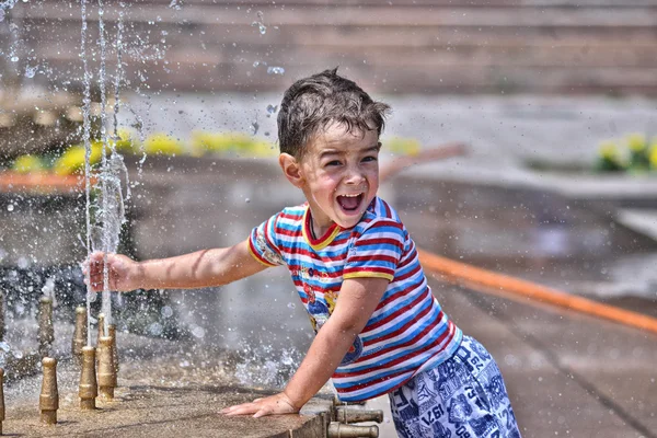 Niño feliz jugando en una fuente de la ciudad — Foto de Stock