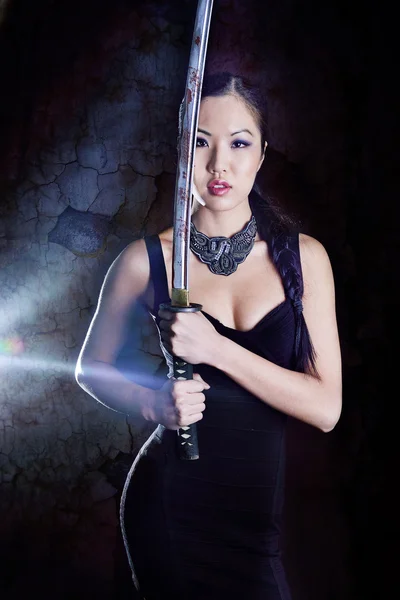 Hermoso modelo en vestido elegante negro con espada — Foto de Stock