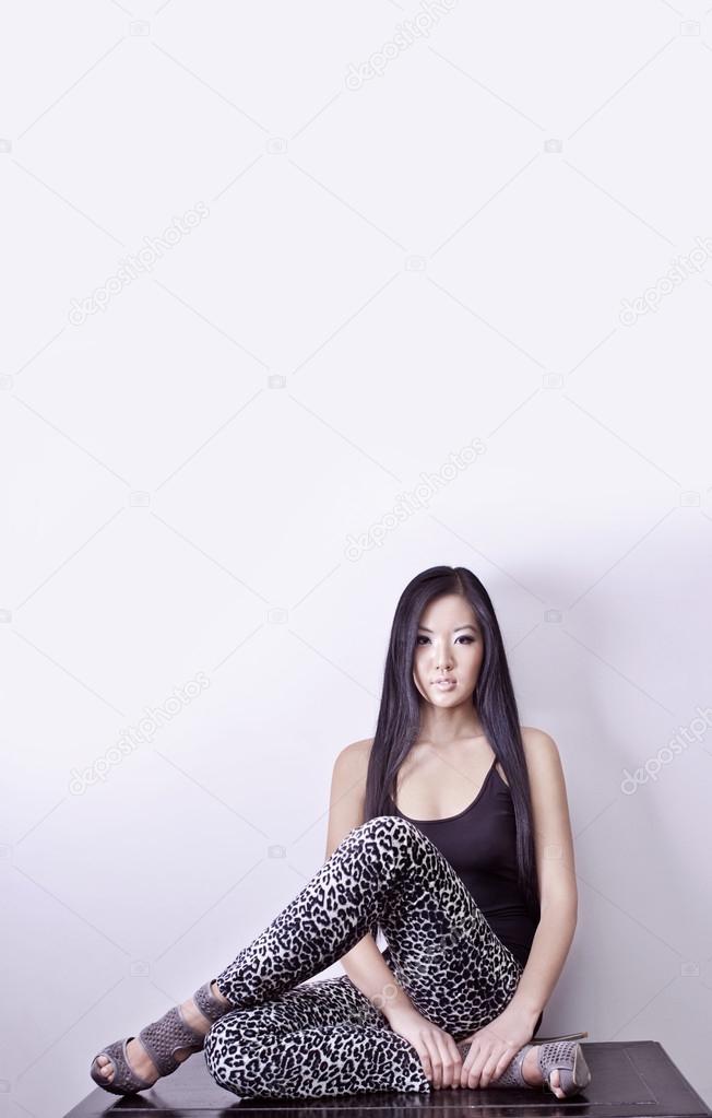 Model in a sitting position on his heels with long hair and leopard pants