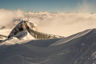 LES DIABLERETS, SİZTERLAND - 10.20.2020: Dünyanın iki dağ zirvesi arasındaki tek asma köprüsü olan Buzul 3000 alanı. İnsanlar köprüde fotoğraf çekiyor. Ünlü simgeler..