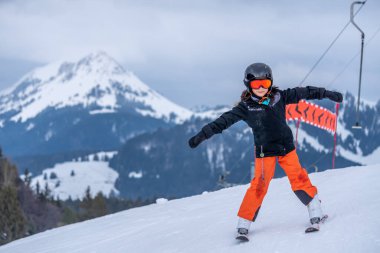 Karda kayak yapmak. Asyalı bir kız halatı tutarak ve kayak sopalarını tutarak asansörde oturuyor. İsviçre 'de tatil. Mutlu çocukluk.