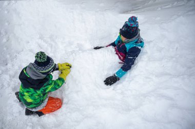 Karda oynayan çocuklar. Kışın karda gömülü iki Asyalı çocuk. Mutlu bir çocukluk ve eğlence. Zermatt, İsviçre.