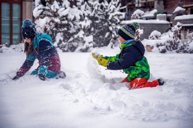 Çocuklar karla oynuyor. Kışın kar atan iki Asyalı çocuk. Mutlu çocukluk ve birliktelik. Zermatt, İsviçre.