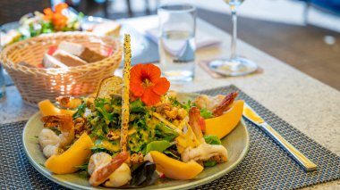 Açık havada kavunlu, karidesli ve yenilebilir çiçekli taze yaz salatası. Sağlıklı beslenme kavramı.