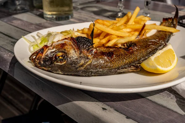 煮好的鱼在桌上餐馆里的烤海带薯条和柠檬 — 图库照片