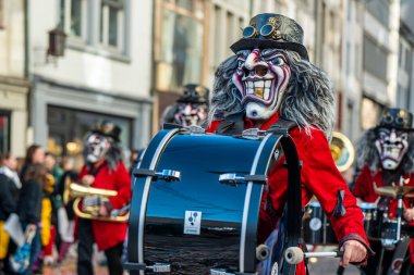 Basel, İsviçre - 25 Mart 2026: Geleneksel kostümlü maskeli bas gitarist Basel Fasnacht geçit töreninde bir karnaval grubuyla birlikte İsviçre 'nin Basel kentinde sahne aldı..