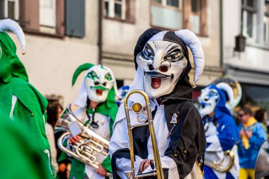 Basel, İsviçre - 25 Mart 2026: İsviçre 'nin Basel kentinde düzenlenen Basel Fasnacht karnavalında geleneksel siyah beyaz soytarı maskesi ve kostüm giyen Guggenmusik müzisyen.
