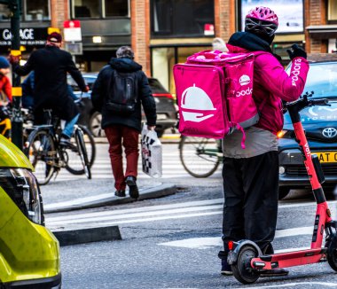 İsveç 'in merkezindeki Foodora i Stockholm şirketinden yiyecek teslimatı yapan elektrikli scooterlı bir kurye..