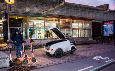 İsveç 'in merkezindeki Stockholm' de kiralık elektrikli scooterlarda hizmet ve akü değişimi. Elektrikli kargo scooter kullanan bir asker tarafından sahnelenmiş..