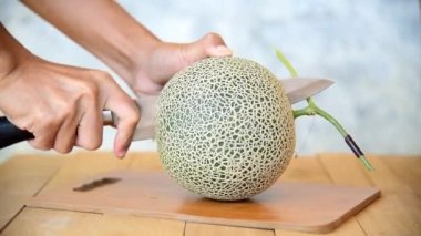 Bıçak kullanan adam portakallı karpuzu ahşap tabakta ikiye böldü.