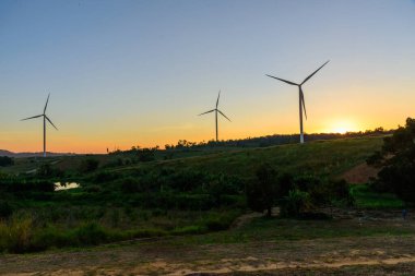 Rüzgar türbinleri günbatımında rüzgardan elektrik üretmek için park ederler.