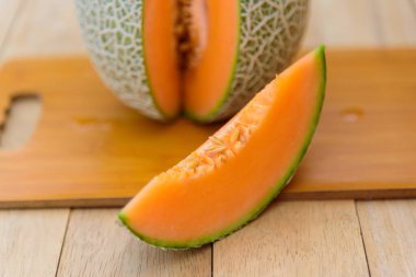 Portakal karpuzunu ahşap tabakta bölmek için yakın plan.