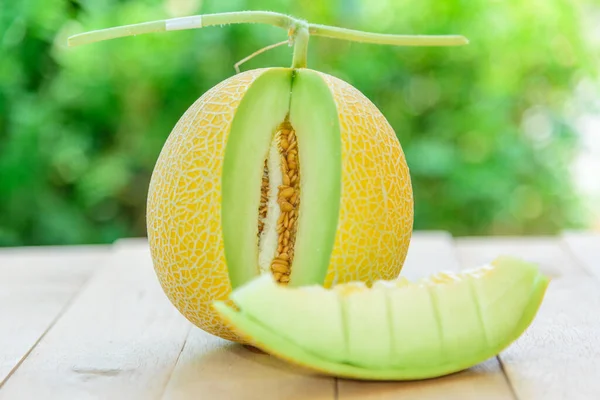 Closeup to split the yellow galia melon on wood plate / Golden emeral melon