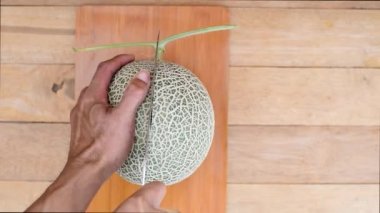 Bıçak kullanan adam portakallı karpuzu ahşap tabakta ikiye böldü.