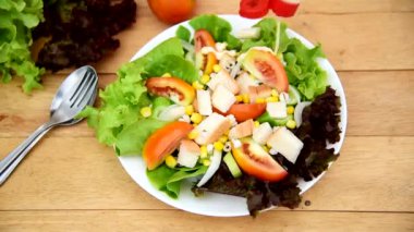 Pour salad cream to Mixed fresh vegetables salad in white dish on wood plate