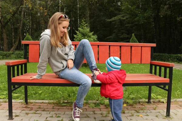 Küçük bir çocuk annesi ve ayakkabı parkta kravat yardımcı olur