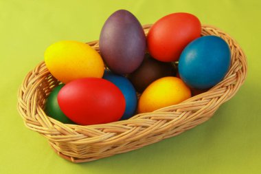Tatil hazırlığı için ahşap sepet süslemesine boyanmış renkli Paskalya yumurtaları. Tavuk veya ördek yumurtası boyamak tüm dünyada Paskalyayı kutlamak için yapılan bir Hıristiyan geleneğidir..