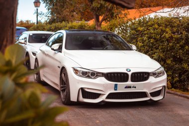 Vallines, Cantabria, İspanya - 23 Ekim 2020: Cantabria 'da düzenlenen süper spor araçları sergisinde park edilmiş beyaz BMW M4. BMW 4 Serisi, üreticisi BMW 'nin 2013 yılında satışa sunduğu lüks bir spor otomobil.