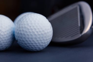 Golf topu ve demir sopa çok yakın görünüyor. Siyah arkaplan