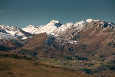 Karlı dağları olan Puentenansa Vadisi Cantabria. Sağ altta güçlendirilmiş kulesi olan Obeso kasabası.