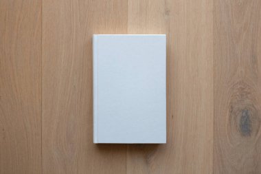 Boş kapaklı bir kitap ve yukarıdan görünen tahta bir zeminde boş bir kapak.