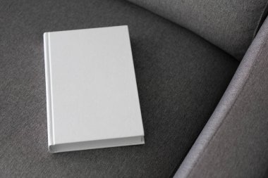 Boş kapaklı bir kitap ve gri bir kanepede boş bir kapak.