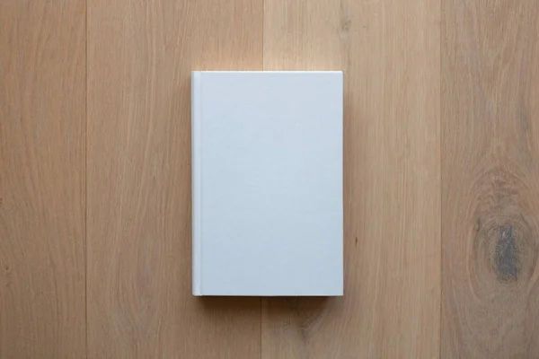 Book with blank cover and empty cover on a wooden floor seen from above