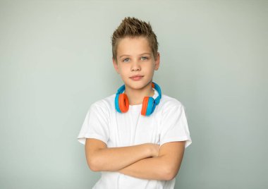 Yakışıklı çocuk kollarını göğsünde kavuşturdu ve kameraya baktı. Genç kızın boynunda kulaklık var. Beyaz gömlekli adam. İzole edilmiş. Gri arkaplan