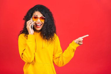 Çekici kıvırcık saçlı, kıvırcık saçlı, akıllı telefon ekranında tedirgin, arkadaşından gelen mesaj içeriğinden etkilenmiş, şaşırmış bir yüz ifadesi var..