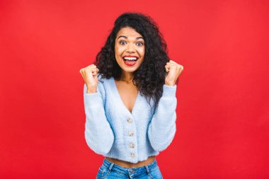 Mutlu galip! Kırmızı arka planda izole edilmiş başarıyı kutlayan mutlu, genç, Afro-Amerikan siyahi bir kadının portresi. 