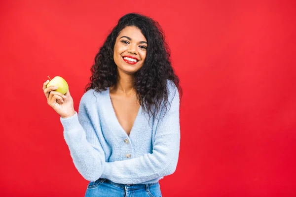 Joven Mujer Afroamericana Comiendo Manzana Verde Aislada Sobre Fondo Rojo — Foto de Stock