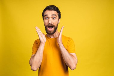 Mutlu galip! Şok olmuş genç bir erkeğin portresi ağzını açık tutar, şaşırır ve büyük bir şaşkınlık yaratır. Pembe sarı arkaplanda izole edilmiş..