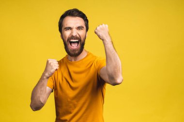 Mutlu galip! Şok olmuş genç bir erkeğin portresi ağzını açık tutar, şaşırır ve büyük bir şaşkınlık yaratır. Sarı arkaplan üzerinde izole edilmiş.