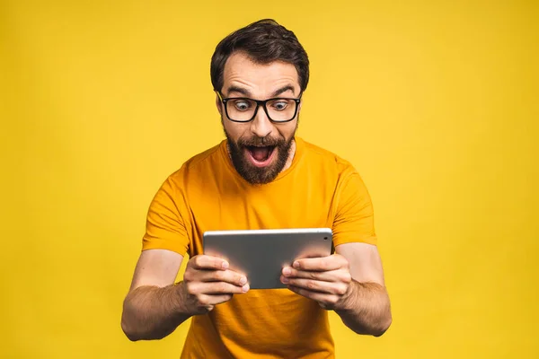 惊喜交集的大胡子男人用数字平板电脑对社交媒体的新闻感到震惊 惊讶的男人购物者对网上黄色背景的孤立的胜利感到惊讶 — 图库照片